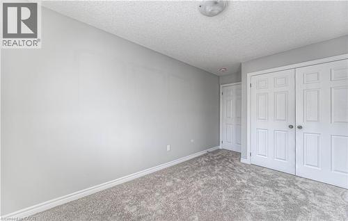 Neutral-toned carpeting paired with light gray walls, white baseboards, and a white six-panel bifold closet door - 44 Harrison Drive, Cambridge, ON - Indoor Photo Showing Other Room
