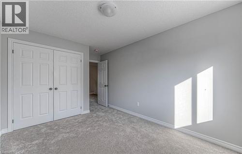 Neutral gray wall paint with white trim, light gray carpet flooring, and a white six-panel bi-fold closet door - 44 Harrison Drive, Cambridge, ON - Indoor Photo Showing Other Room