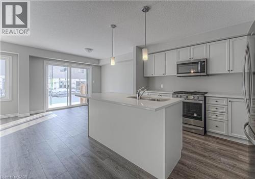 Modern kitchen featuring light gray cabinetry, stainless steel appliances, a center island with sink, and pendant lighting - 44 Harrison Drive, Cambridge, ON - Indoor
