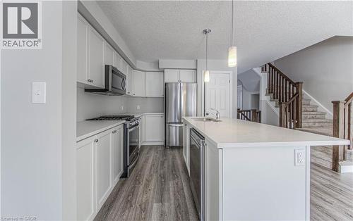 Modern kitchen featuring an extended island with a built-in sink and pendant lighting - 44 Harrison Drive, Cambridge, ON - Indoor Photo Showing Kitchen With Stainless Steel Kitchen With Upgraded Kitchen