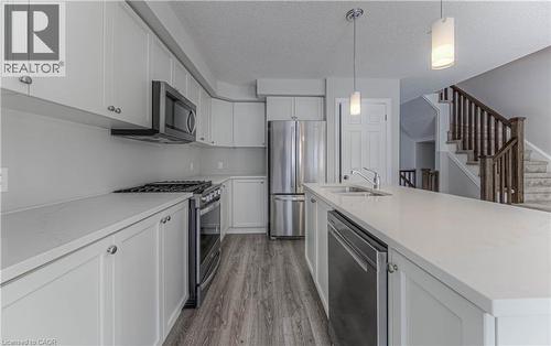 Kitchen featuring light cabinetry, stainless steel appliances, an island with an undermount sink, pendant lighting, and wood-finish flooring - 44 Harrison Drive, Cambridge, ON - Indoor Photo Showing Kitchen With Stainless Steel Kitchen With Double Sink With Upgraded Kitchen