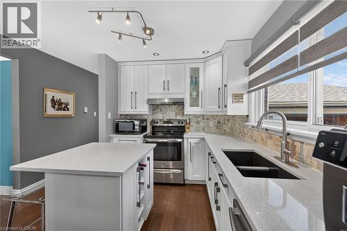 Modern kitchen featuring white cabinetry with brushed nickel hardware, light-toned countertops, wood-finish flooring, a mosaic tile backsplash, and recessed lighting - 386 Upper Kenilworth Avenue, Hamilton, ON - Indoor Photo Showing Kitchen With Stainless Steel Kitchen With Double Sink With Upgraded Kitchen