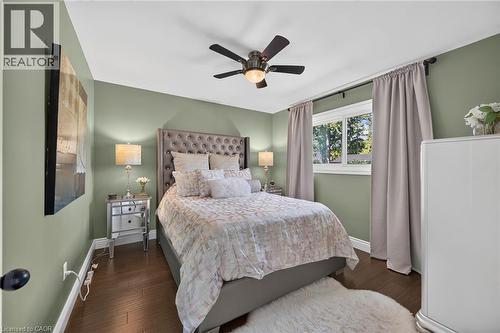 Wood-finish flooring with baseboard trim, wall-mounted ceiling fan, and a double-pane window - 386 Upper Kenilworth Avenue, Hamilton, ON - Indoor Photo Showing Bedroom