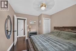 Spacious room featuring wood-finish flooring, a contemporary ceiling fan, and a paneled white door - 