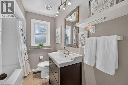 Bathroom featuring a white ceramic bathtub with shower, a single white vanity with an integrated sink and dark wood-finish cabinetry, and a white toilet - 386 Upper Kenilworth Avenue, Hamilton, ON - Indoor Photo Showing Bathroom