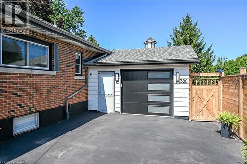 Attached garage with modern black door featuring frosted glass panels, complemented by white siding and contemporary outdoor lighting fixtures - 386 Upper Kenilworth Avenue, Hamilton, ON - Outdoor