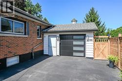Attached garage with modern black door featuring frosted glass panels, complemented by white siding and contemporary outdoor lighting fixtures - 