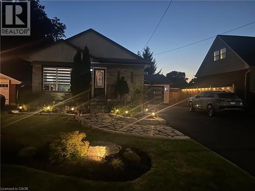 Stone facade home featuring a flagstone walkway, paved driveway, mature landscaping, and exterior accent lighting - 386 Upper Kenilworth Avenue, Hamilton, ON - Outdoor