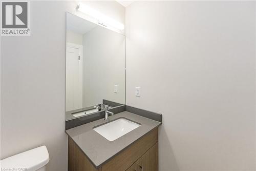 Modern vanity featuring wood-finish cabinetry, a solid surface countertop with integrated sink, and brushed chrome faucet - 72 Erb Street E Unit# 103, Waterloo, ON - Indoor Photo Showing Bathroom