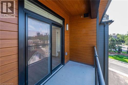 Private balcony featuring a wood-panel accent wall and a concrete floor - 72 Erb Street E Unit# 103, Waterloo, ON - Outdoor With Balcony With Exterior