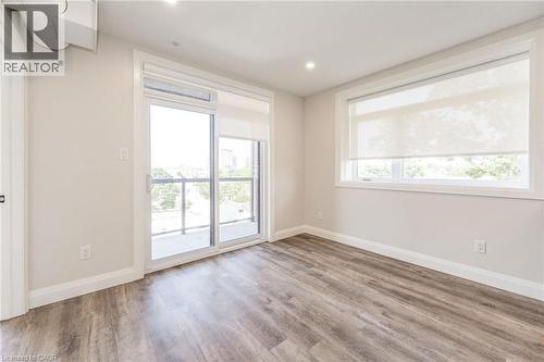 Bedroom featuring a sliding glass door leading to an outdoor space, wood-finish flooring, a large window, recessed lighting, and neutral wall tones - 72 Erb Street E Unit# 103, Waterloo, ON - Indoor Photo Showing Other Room