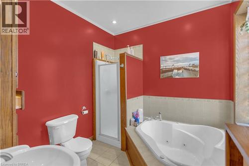 Bathroom featuring a jetted soaking tub, walk-in shower with frosted glass enclosure, and wood-finish cabinetry - 17 Scarfe Avenue, Brantford, ON - Indoor Photo Showing Bathroom