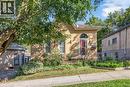 Light-toned brick exterior with an arched entry door and a covered front porch featuring wrought iron railing - 17 Scarfe Avenue, Brantford, ON  - Outdoor 