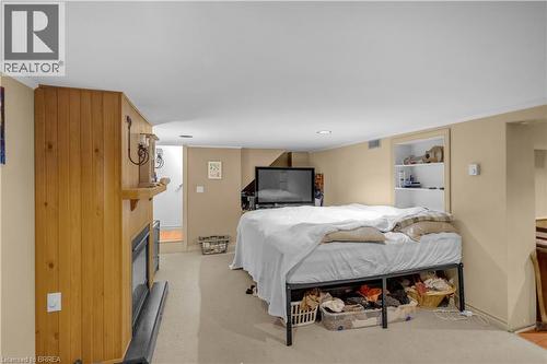 Finished basement area featuring a wood-paneled fireplace surround, recessed lighting, and a built-in shelving unit - 17 Scarfe Avenue, Brantford, ON - Indoor Photo Showing Bedroom