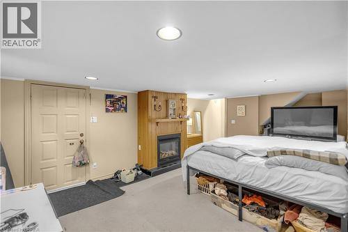 Carpeted room featuring a fireplace with a wood mantel and paneling, recessed lighting, and a six-panel door - 17 Scarfe Avenue, Brantford, ON - Indoor Photo Showing Bedroom With Fireplace