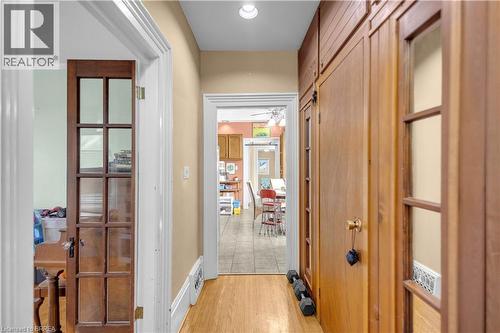 Hallway featuring wood-finish flooring, built-in cabinetry with glass-paneled doors, white baseboards, and neutral wall paint - 17 Scarfe Avenue, Brantford, ON - Indoor Photo Showing Other Room