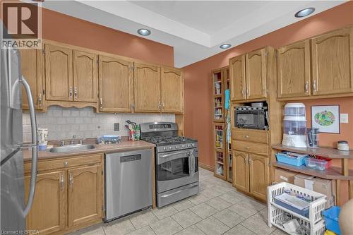 Kitchen featuring extensive wood cabinetry, stainless steel appliances, and a tile backsplash - 17 Scarfe Avenue, Brantford, ON - Indoor Photo Showing Kitchen