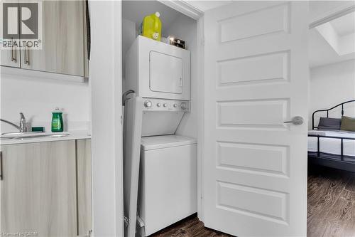 In-unit washer and dryer with stacked configuration, white finish cabinetry above, and convenient shelving for laundry essentials - 158 King Street N Unit# 81201, Waterloo, ON - Indoor Photo Showing Laundry Room