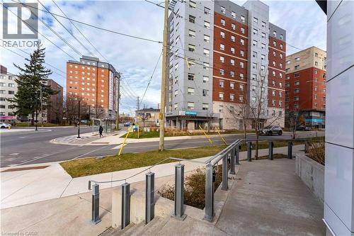 Modern building exterior featuring a concrete walkway, metal railings, and a landscaped perimeter - 158 King Street N Unit# 81201, Waterloo, ON - Outdoor With Facade
