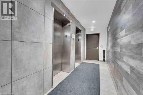 Modern building corridor featuring dual stainless steel elevators with brushed metal finishes, light-toned large-format tile flooring throughout, and contemporary gray textured wall paneling - 158 King Street N Unit# 81201, Waterloo, ON - Indoor Photo Showing Bathroom