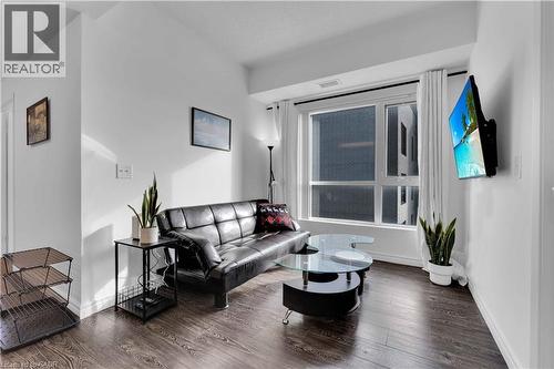 Living area featuring wood-finish flooring, a large window with white curtains, and a wall-mounted flat-screen display - 158 King Street N Unit# 81201, Waterloo, ON - Indoor Photo Showing Living Room
