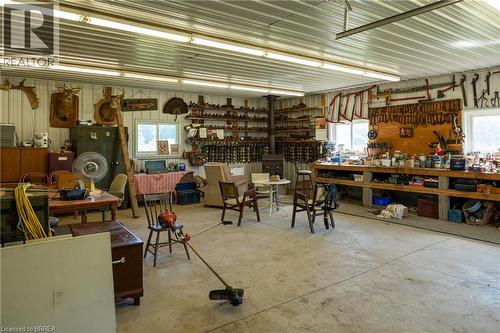 Spacious utility room featuring a concrete floor, corrugated metal ceiling, and fluorescent overhead lighting - 269 Brant County Road 22, Ancaster, ON 