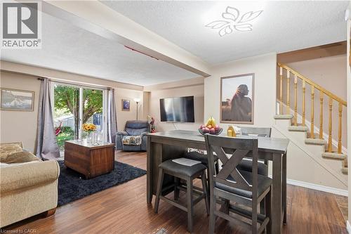 Spacious living area featuring wood-finish flooring, sliding glass patio doors, and a staircase with carpeted treads - 292 Mayview Court Unit# B, Waterloo, ON - Indoor