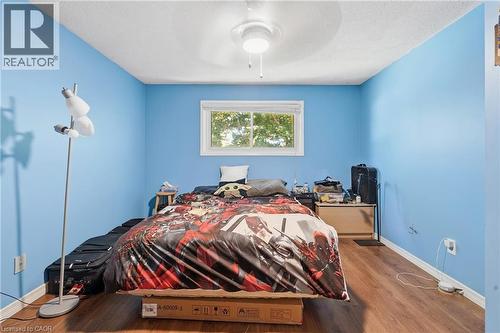 Room featuring wood-finish flooring, a white trim baseboard, and a white framed window - 292 Mayview Court Unit# B, Waterloo, ON - Indoor Photo Showing Bedroom