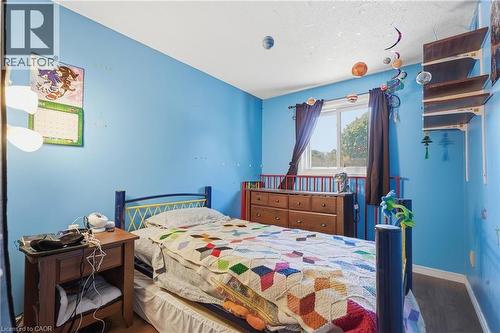 Bright bedroom featuring a single window with dark drapes, wood-finish flooring, and built-in shelving - 292 Mayview Court Unit# B, Waterloo, ON - Indoor Photo Showing Bedroom