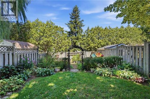 Expansive backyard with a manicured lawn, established garden beds, and mature perimeter trees - 292 Mayview Court Unit# B, Waterloo, ON - Outdoor