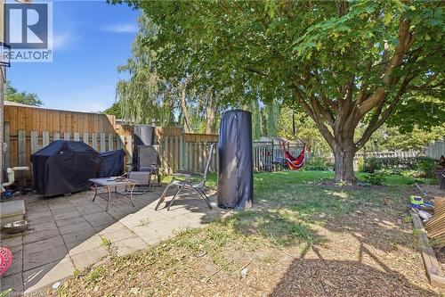 Spacious backyard featuring a paver patio area, mature shade tree, natural grass, and wood privacy fencing - 292 Mayview Court Unit# B, Waterloo, ON - Outdoor