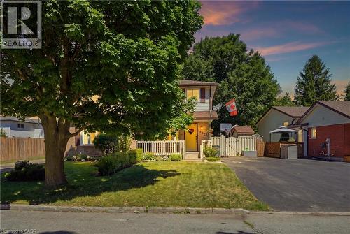 Split-level residence featuring a prominent front porch with white railings, a paved driveway, and established landscaping including a large mature tree - 292 Mayview Court Unit# B, Waterloo, ON - Outdoor