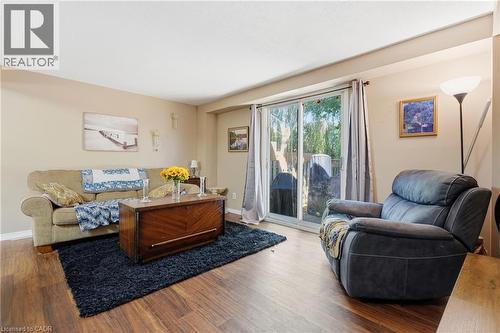 Spacious living room featuring wood-finish flooring, a blue area rug, and abundant natural light from sliding glass doors - 292 Mayview Court Unit# B, Waterloo, ON - Indoor Photo Showing Living Room