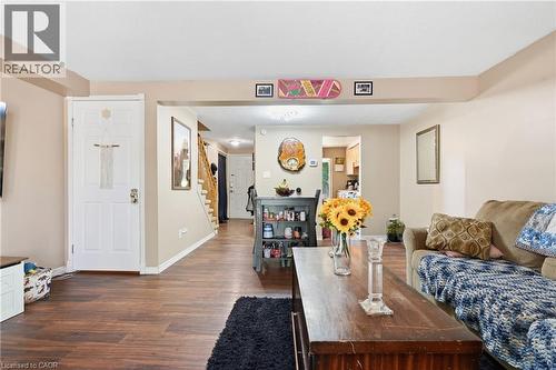 Open-concept living area featuring warm wood-finish flooring throughout, a wood dining table with seating, and abundant natural light from multiple windows - 292 Mayview Court Unit# B, Waterloo, ON - Indoor Photo Showing Living Room