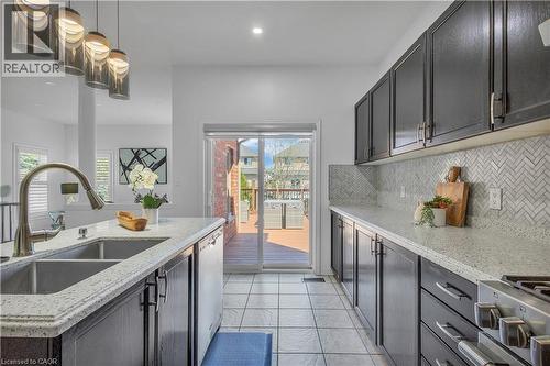 Kitchen featuring dark cabinetry, light speckled countertops, and a herringbone tile backsplash - 73 Fitzgerald Drive, Cambridge, ON - Indoor Photo Showing Kitchen With Double Sink With Upgraded Kitchen
