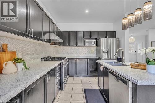 Modern kitchen featuring dark cabinetry, light speckled countertops, and a herringbone tile backsplash - 73 Fitzgerald Drive, Cambridge, ON - Indoor Photo Showing Kitchen With Double Sink With Upgraded Kitchen