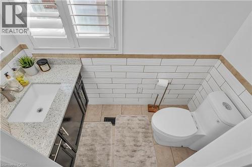 White subway tile wainscoting with a tan border accents this bathroom, featuring a white porcelain toilet - 73 Fitzgerald Drive, Cambridge, ON - Indoor Photo Showing Bathroom