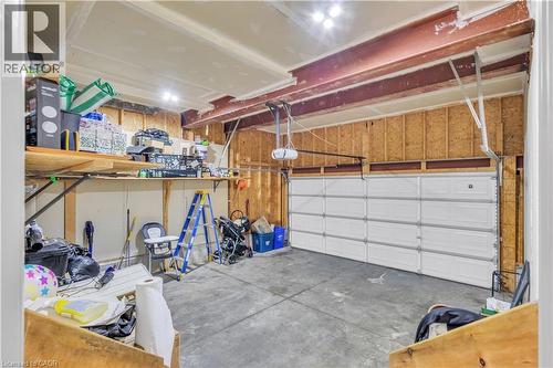 Garage space featuring a paneled overhead door, concrete flooring, exposed wood framing, and an overhead storage shelf - 73 Fitzgerald Drive, Cambridge, ON - Indoor Photo Showing Garage