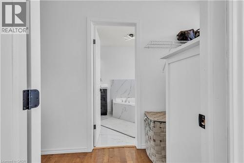 Interior hallway featuring wood-finish flooring transitioning to a bathroom with marble-patterned floor tiles - 73 Fitzgerald Drive, Cambridge, ON - Indoor