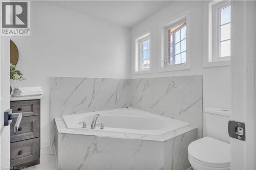 Corner soaking tub with polished chrome fixtures, surrounded by marble-look tile - 73 Fitzgerald Drive, Cambridge, ON - Indoor Photo Showing Bathroom