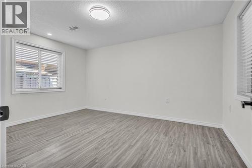 Room featuring wood-finish flooring, crisp white walls, and a recessed window with blinds - 73 Fitzgerald Drive, Cambridge, ON - Indoor Photo Showing Other Room