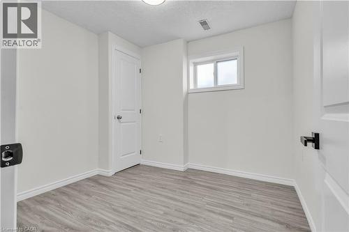 Neutral-toned room featuring light wood-finish flooring, white walls, and a single window - 73 Fitzgerald Drive, Cambridge, ON - Indoor Photo Showing Other Room