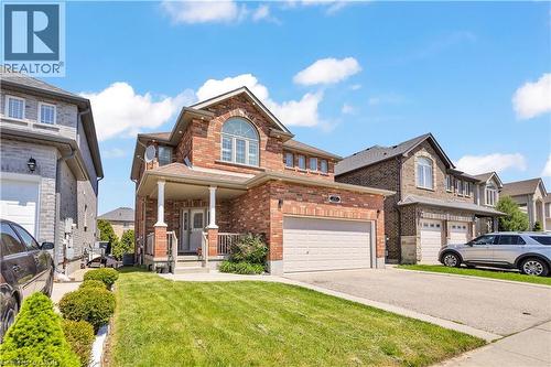 Brick facade residence featuring a covered front porch with white columns, an arched upper-story window, an attached two-car garage, and a concrete driveway - 73 Fitzgerald Drive, Cambridge, ON - Outdoor With Facade
