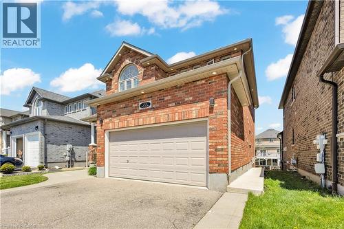 Red brick exterior featuring a light-colored garage door and an arched window on the upper level - 73 Fitzgerald Drive, Cambridge, ON - Outdoor