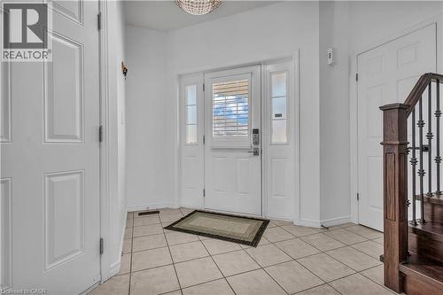 Front entry with tile flooring, a solid core entry door featuring sidelights, and a wood staircase with wrought iron balusters - 73 Fitzgerald Drive, Cambridge, ON - Indoor Photo Showing Other Room