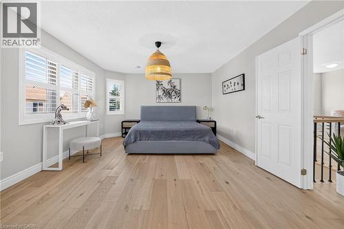 Spacious room featuring light wood-finish flooring, multiple windows with white plantation shutters, and a woven pendant light fixture - 1533 Morse Place, Milton, ON - Indoor
