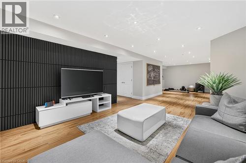 Spacious recreation area featuring wood-finish flooring, recessed lighting, a modern black accent wall, and a built-in media console - 1533 Morse Place, Milton, ON - Indoor