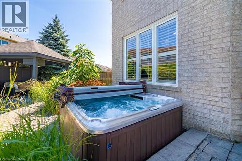 Luxurious backyard retreat featuring a built-in hot tub with integrated seating and jets, positioned on a stamped concrete patio - 1533 Morse Place, Milton, ON - Outdoor
