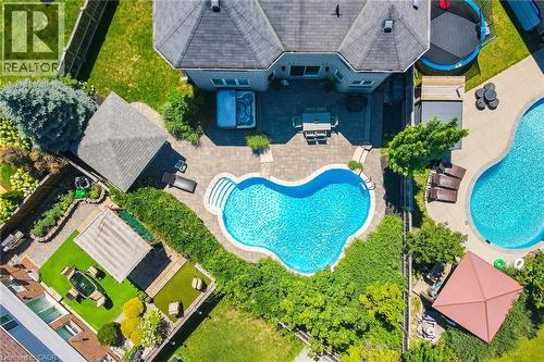 Aerial view of this residence showcasing a resort-style backyard retreat featuring a custom kidney-shaped swimming pool with sun deck, mature landscaping with established trees and lush lawn areas, ci - 1533 Morse Place, Milton, ON - Outdoor With In Ground Pool With Deck Patio Veranda