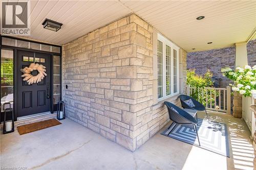 Stone veneer exterior with a covered porch featuring a black paneled entry door with transom and sidelights, a white column, and white window trim - 1533 Morse Place, Milton, ON - Outdoor With Deck Patio Veranda With Exterior